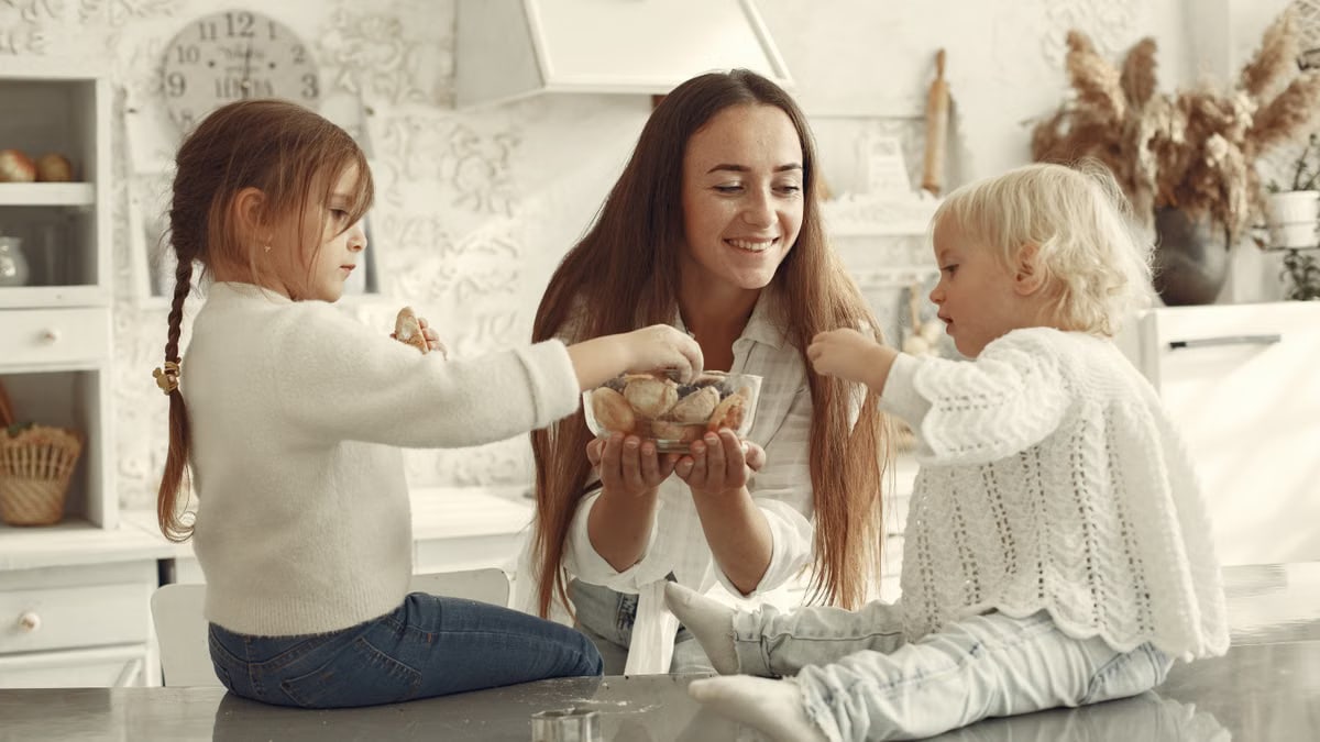A joyful mother and her two children enjoy baking cookies together in a cozy home kitchen.